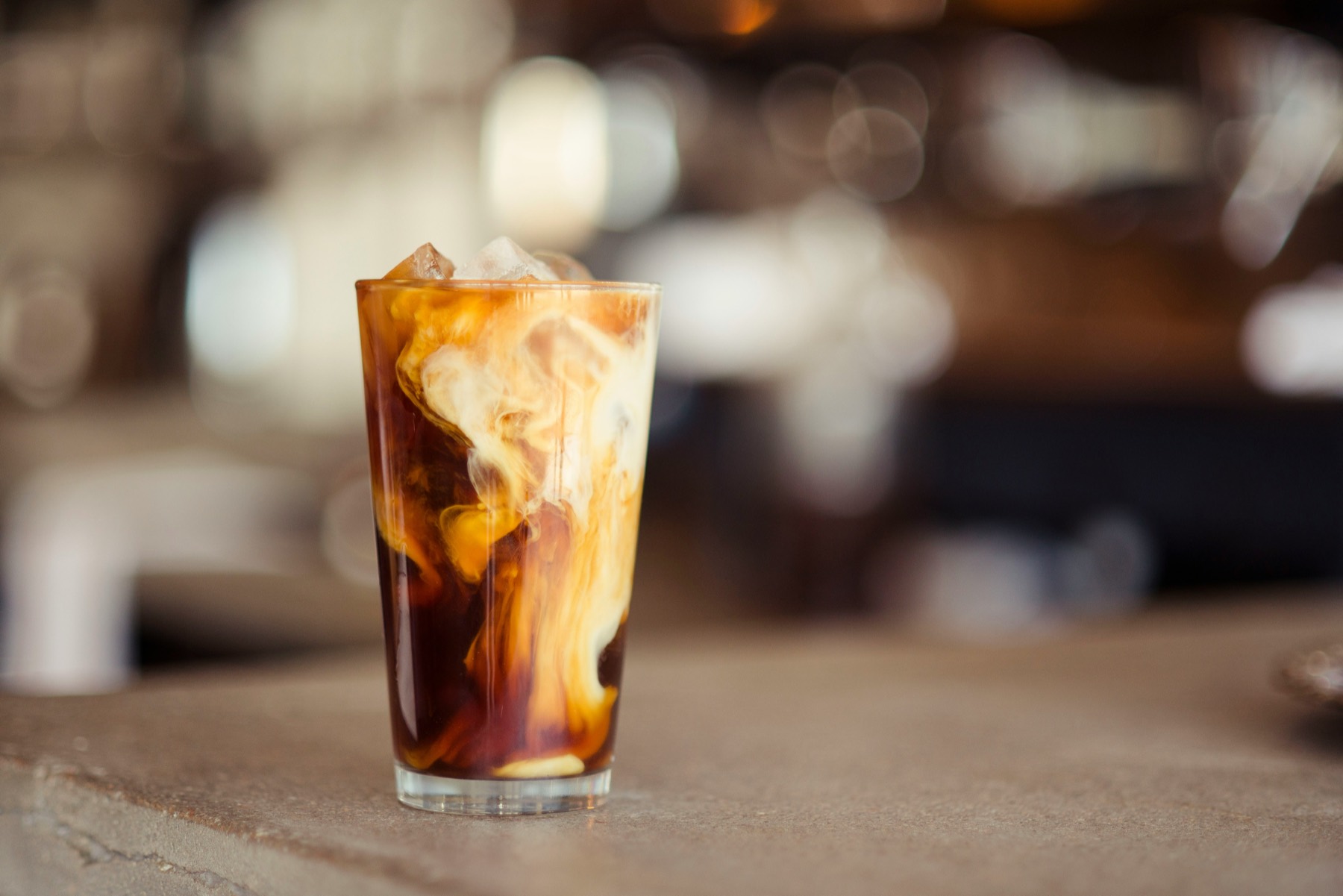 Iced latte held up in front of the Salted Sisters coffee-ring wall logo
